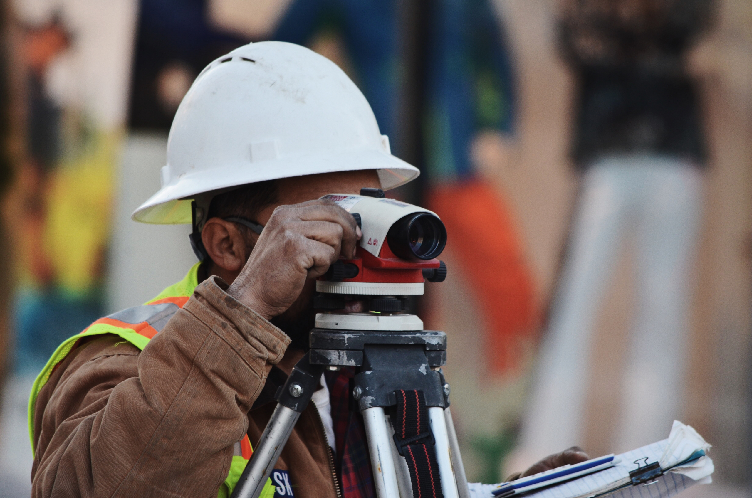 Man wearing a hard hat using a surveying device